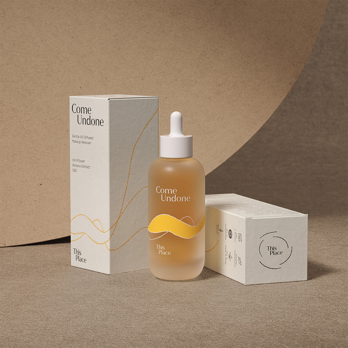 Ein Glasflakon mit der Aufschrift Come Undone zwischen zwei Umverpackungen des Produktes, eine stehend und eine davon liegend